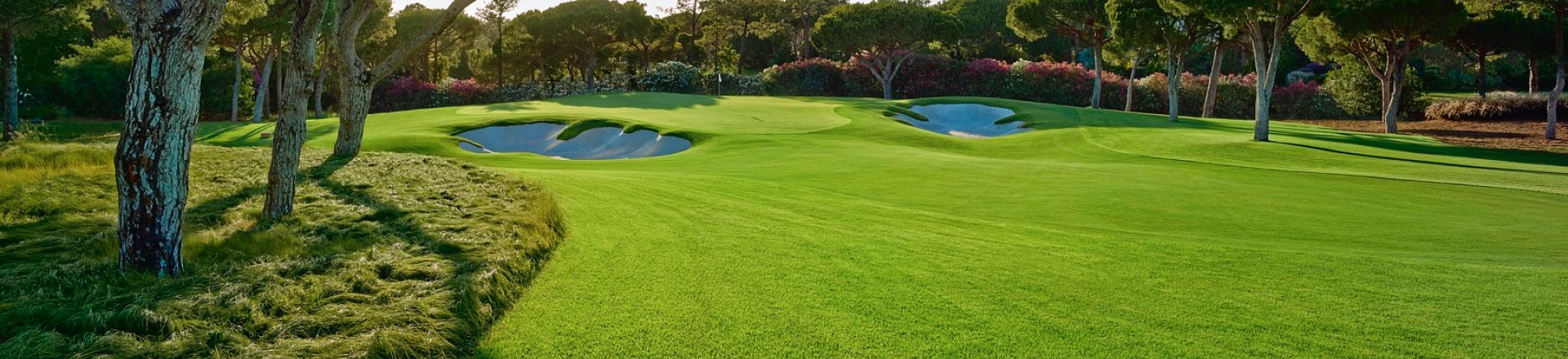 A golf course with green grass and a white bunker in a great golf holiday destination